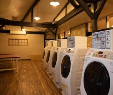 Front-loading washers and wooden benches in HOTEL SHIRAHAMAKAN laundry room, Wakayama