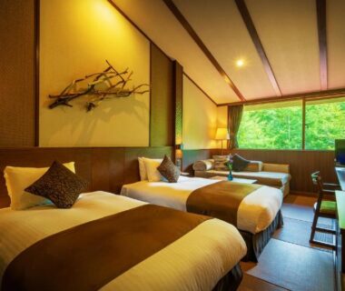 Twin beds on tatami with shoji window and lush greenery outside at Hachimantai Mountain Hotel, Iwate