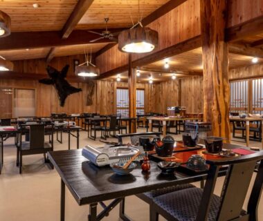 Spacious wooden dining hall with set trays and tableware at Hacho no Yu in Tochigi, Kantō