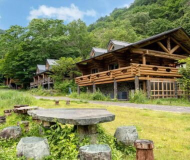 Wooden ryokan buildings with verandas and a grassy courtyard at Hacho no Yu, mountain setting in Tochigi, Kantō, Japan