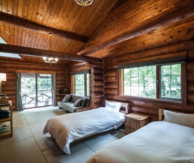 Wooden log interior with exposed beams, two beds and sliding glass doors opening to forest, Hacho no Yu, Tochigi