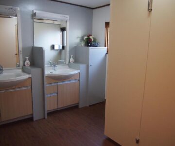 Shared wash area with two sinks, mirrors and small refrigerator at Hagurokan in Yamagata Tōhoku