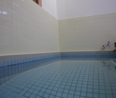 Indoor blue-tiled bath with wall-mounted faucets and high tiled walls at Hagurokan Yamagata