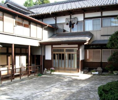 Traditional wooden facade and tiled roof with paved entrance courtyard at Hagurokan in Yamagata prefecture
