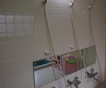 Three tiled shower stations with low mirrors and buckets at Hagurokan in Yamagata, Tohoku