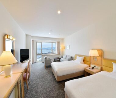 Twin room with two beds at Hakodate Kokusai Hotel Hokkaidō, desk and window with distant city and water view