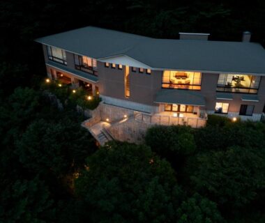 Aerial night view of illuminated multi-story ryokan building surrounded by dense trees in Hakone, Kanagawa