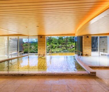 Large indoor onsen with wooden ceiling, stone floor and garden view at Hakone Ashinoko Hanaori, Kanagawa