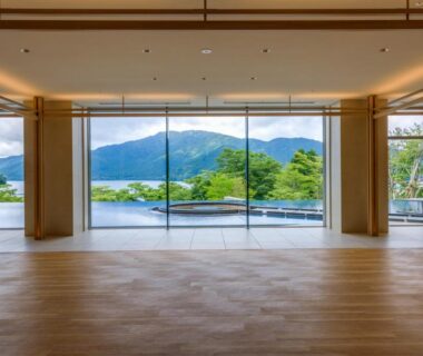 Spacious wooden-floor lobby with floor-to-ceiling windows overlooking lake and mountains at Hakone Ashinoko Hanaori