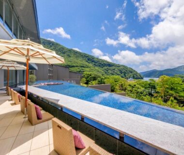 Outdoor pool terrace with umbrellas and loungers overlooking lake and lush mountains at Hakone Ashinoko Hanaori, Kanagawa