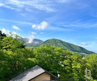 Forest-covered hills and blue sky above a building roof at Hakone Fura in Kanagawa, Kanto, Japan