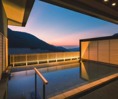 Outdoor onsen bath with wooden screens overlooking mountain silhouette at dusk in Hakone, Kanagawa