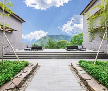 Symmetrical courtyard walkway flanked by greenery and stone beds at Hakone Gora KARAKU, Kanagawa with mountain backdrop
