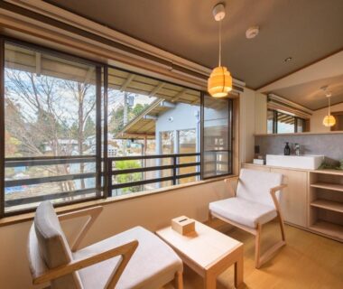Two lounge chairs and table by large window with view of trees, room interior at Hakone Gora TEN, Kanagawa, Japan