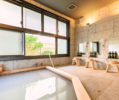 Indoor stone onsen with stools, shower stations and large windows at Hakone Gora Ten, Kanagawa
