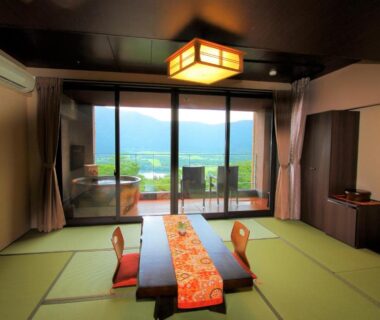 Traditional tatami room with low table, floor chairs and balcony overlooking mountains at Hakone Hoshi no Akari in Kanagawa