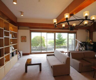 Ryokan lounge with sofas, bookshelves and sliding doors to garden at Hakone Hoshi no Akari in Kanagawa