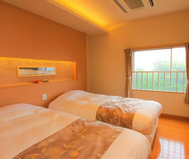 Twin beds with warm ambient lighting, window overlooking trees, wall-mounted TV and polished wood floor