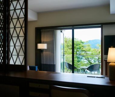 Interior with wooden desk, shoji screen, sliding doors to balcony with chairs and green mountain view, Hakone Hotel, Kanagawa