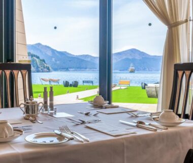 Elegant dining table set with white linens and cutlery, floor-to-ceiling windows framing lake and mountains at Hakone Hotel