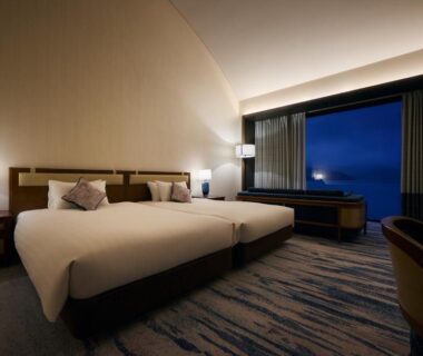 Twin beds, bedside lamps, desk and large window at Hakone Hotel in Kanagawa, Kantō