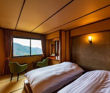 Twin beds on tatami floor with green chairs and mountain view at Hakone Kyuan in Kanagawa