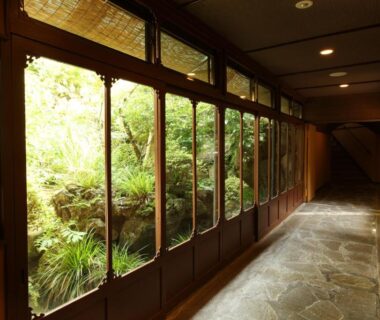 Wood-framed corridor with windows overlooking a lush interior garden at Hakone Onsen Ryokan Yaeikan, Kanagawa