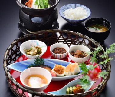 Assorted small Japanese dishes in woven tray with nabe pot at Hakone Onsen Ryokan Yaeikan, Kanagawa