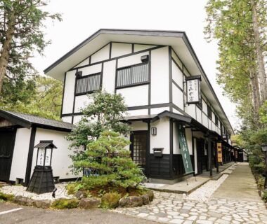 Two-story white ryokan exterior with stone path, lanterns and tall trees at Hakone Onsen Yuyado Yamanoshou, Kanagawa