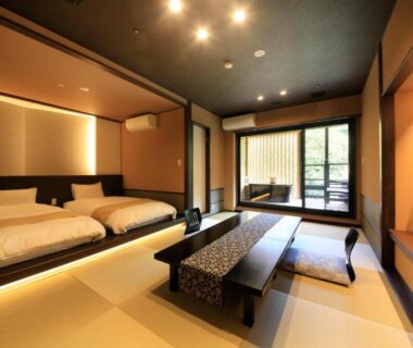 Spacious tatami room with two beds, low table and large window at Hakone Suimeisou Kanagawa
