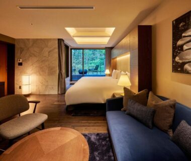 Western-style room with double bed, sofa seating and large window overlooking greenery at Hakone Suishoen in Kanagawa