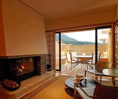 Tatami seating area with fireplace and glass doors opening to terrace and distant hills at Hakone Tokinoshizuku, Kanagawa
