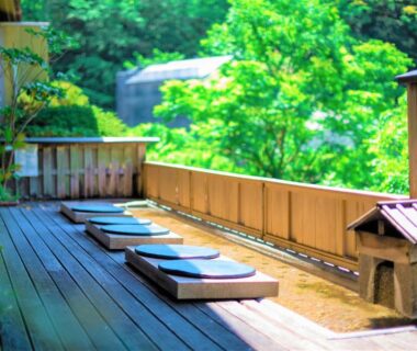 Wooden outdoor terrace with shallow soaking tubs and cushions at Hakone Yumoto Onsen Hotel Kajikaso, Kanagawa