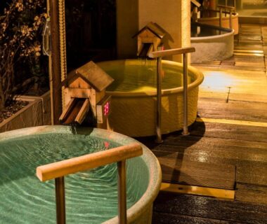 Outdoor circular wooden onsen tubs along a walkway at Hakone Yumoto Onsen Hotel Kajikaso in Kanagawa