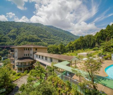 Buildings and outdoor pool amid forested mountains at Hakonenomori Okada, Kanagawa