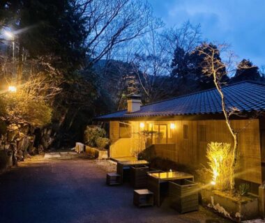 Warmly lit exterior with outdoor seating at Hakonesaryo Kintoki in Kanagawa's wooded setting