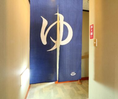Blue noren with bath symbol hanging in ryokan corridor at Hakuraiso, Nagano