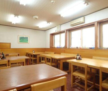 Wooden tables and chairs in Hakuraiso dining room with windows and condiments Nagano