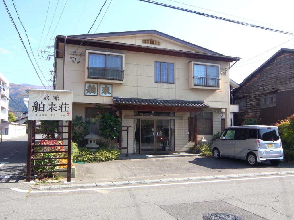 Front entrance Hakuraiso Nagano Chūbu Japan Two-story ryokan exterior with entrance, signage and parked car on street in Hakuraiso, Nagano, Chūbu