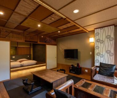 Japanese-style room with tatami, low table, seating, shoji partitions and futon bedding in adjacent alcove