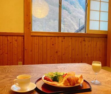 Breakfast tray and drink on wooden table by window with mountain view and shoji screen at Hakuunsou