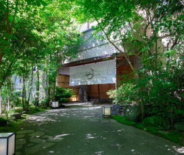 Tree-lined stone path leading to Hakuunsou entrance with noren curtain and lanterns in Kanagawa