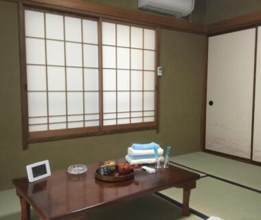 Traditional tatami room with low wooden table, shoji screens and sliding doors at Hamayuu in Shizuoka