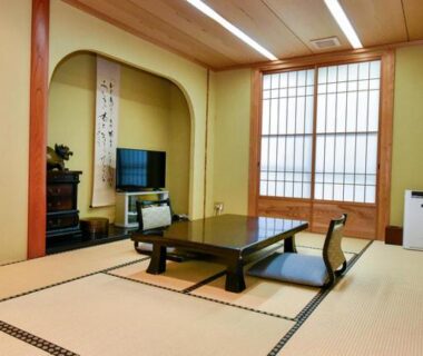 Traditional tatami room with low wooden table, floor chairs, shoji screens and tokonoma alcove at Hamazen Ryokan in Kumamoto