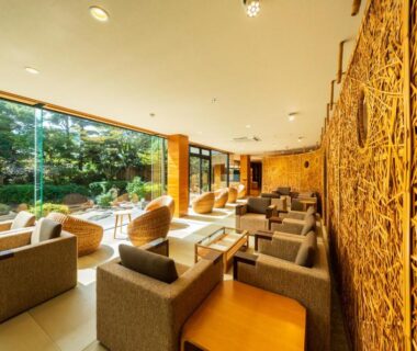 Lounge seating with armchairs facing a landscaped garden at Hana Beppu, Ōita, Kyūshū