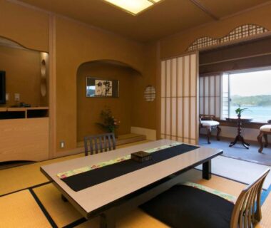 Traditional tatami room with low table, shoji screens and seating overlooking coastal waters in Wakayama