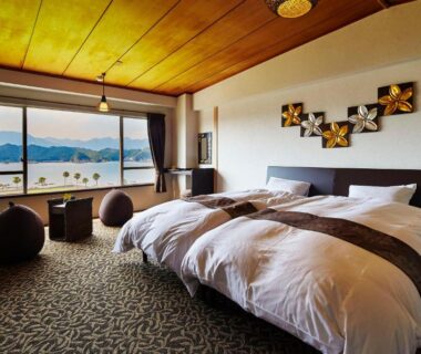 Twin beds in room at Hana Irodori no Yado Kayuu, Wakayama, large panoramic window overlooking water and distant hills