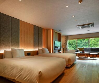 Twin beds on wooden floor with window seating and garden view at HanaMOMIJI Hokkaidō Japan