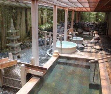 Wooden and stone onsen baths along a covered outdoor corridor at Hanabishi Hotel in Hokkaidō