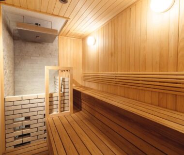 Interior wooden sauna with tiered benches and heater, warm ambient lighting at Hanabishi Hotel in Hokkaido, Japan